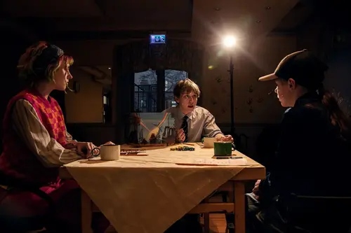 En spelledare och två spelare sitter i ett mysbelyst rum och spelar Mutant år noll